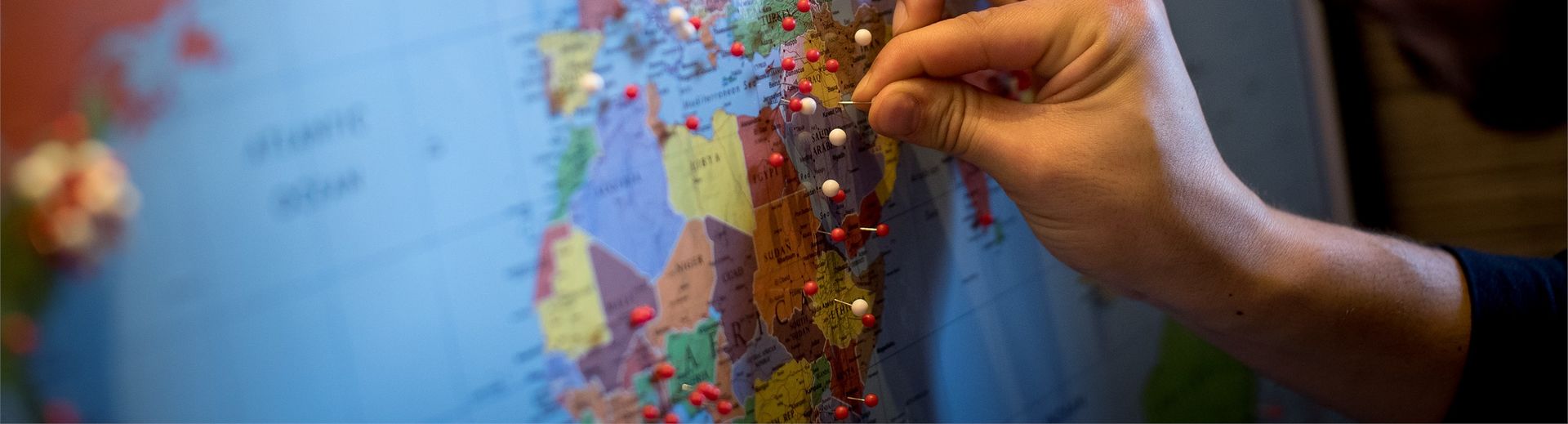 A man placing a pin in a world map. 