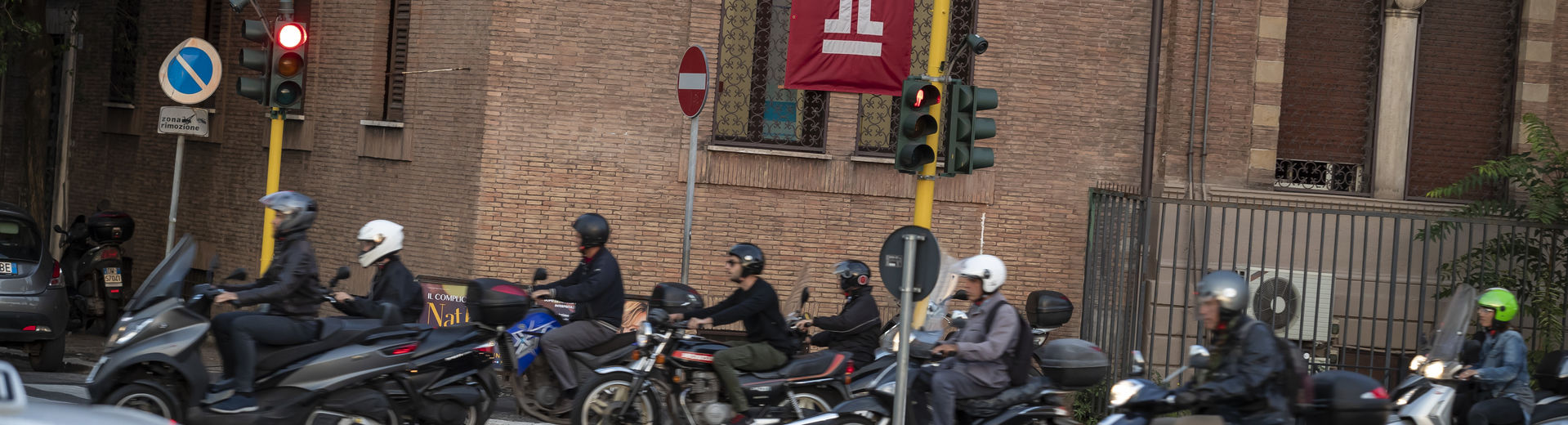 A group of people on motorcycles on an Italian street near Temple Rome.