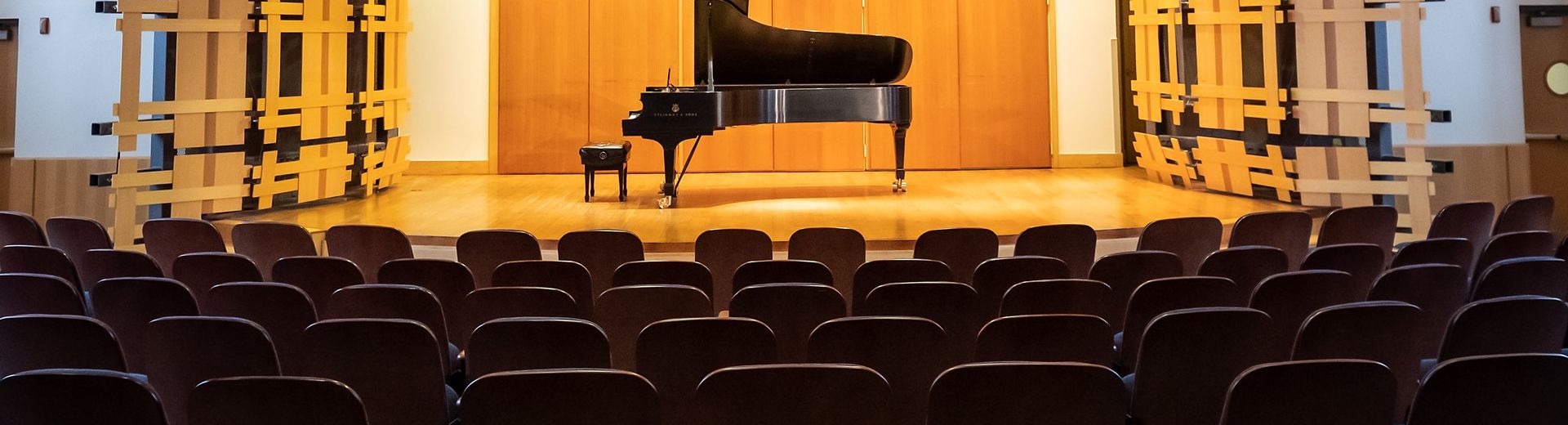 An unattended piano on a stage in an empty auditorium. 