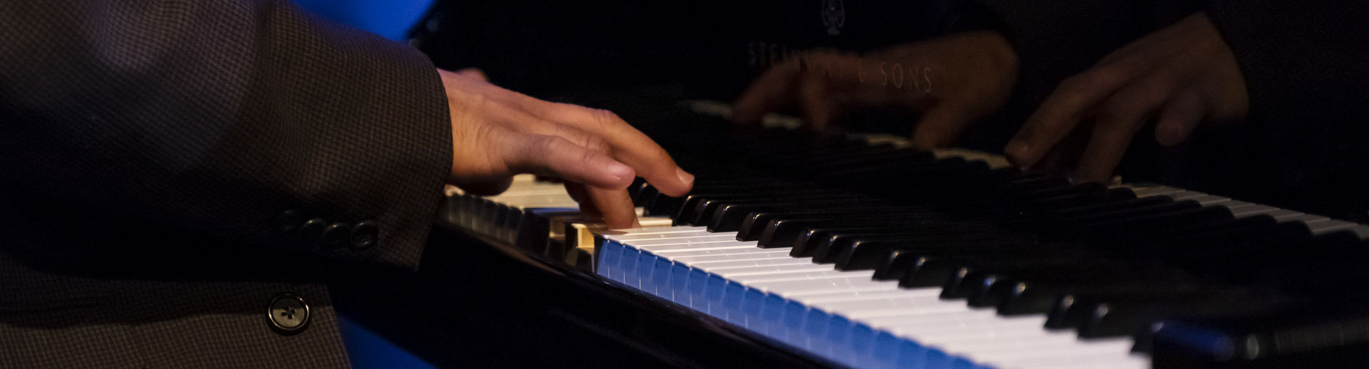 Hands are seen playing the piano.