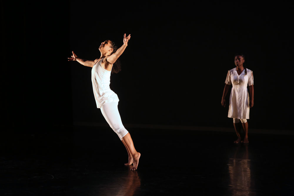 A dancer leaps on stage, with another standing behind her. 